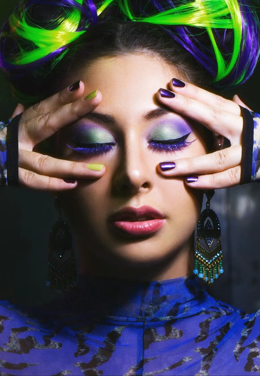 Woman with violet eyeshadow covering her eyes with purple nails