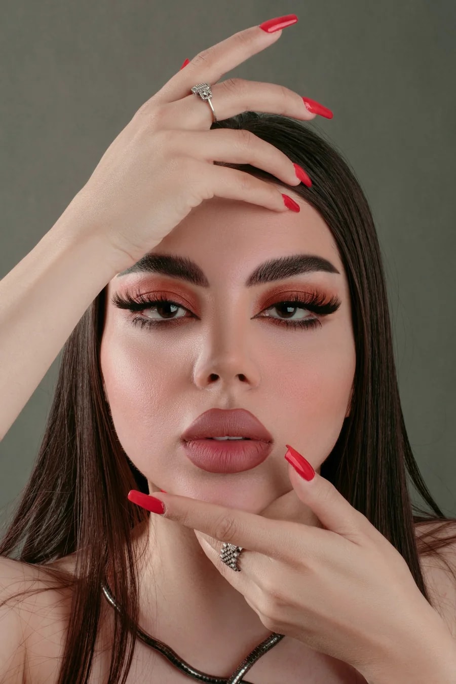 Model framing her face with deep red nails